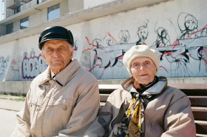 a man and woman standing in front of a wall with graffiti